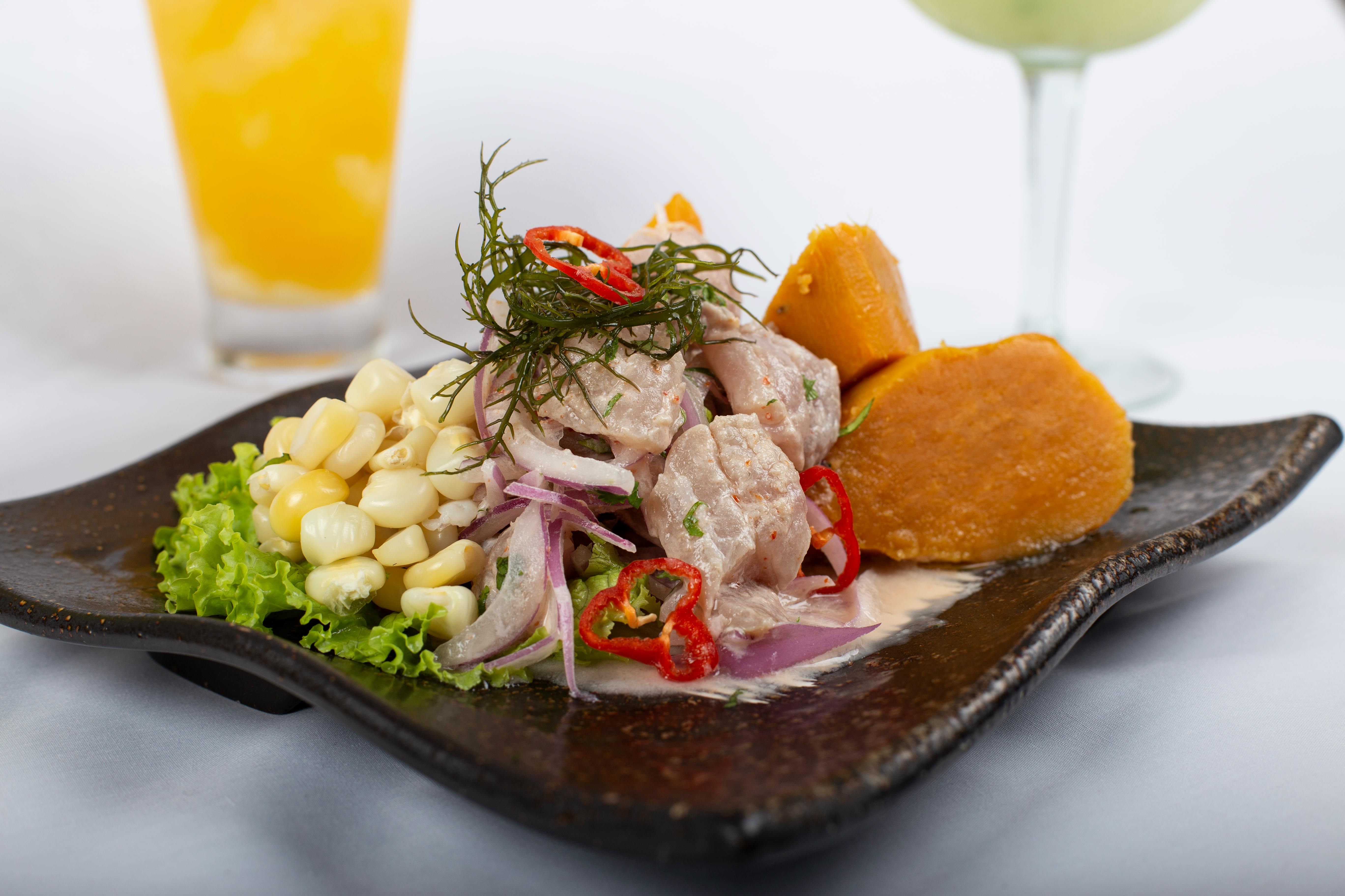 Raw fish in coconut milk with vegetables on the side on a modern ceramic plate